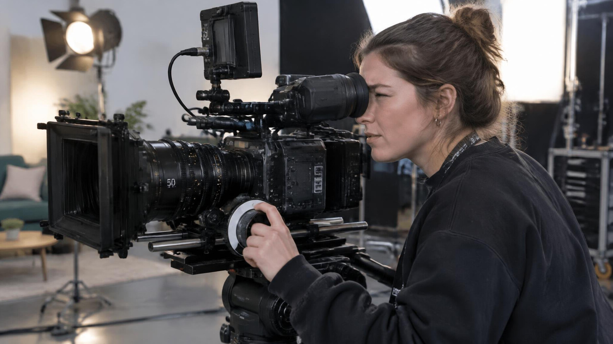Camera operator framing a shot through a viewfinder on set