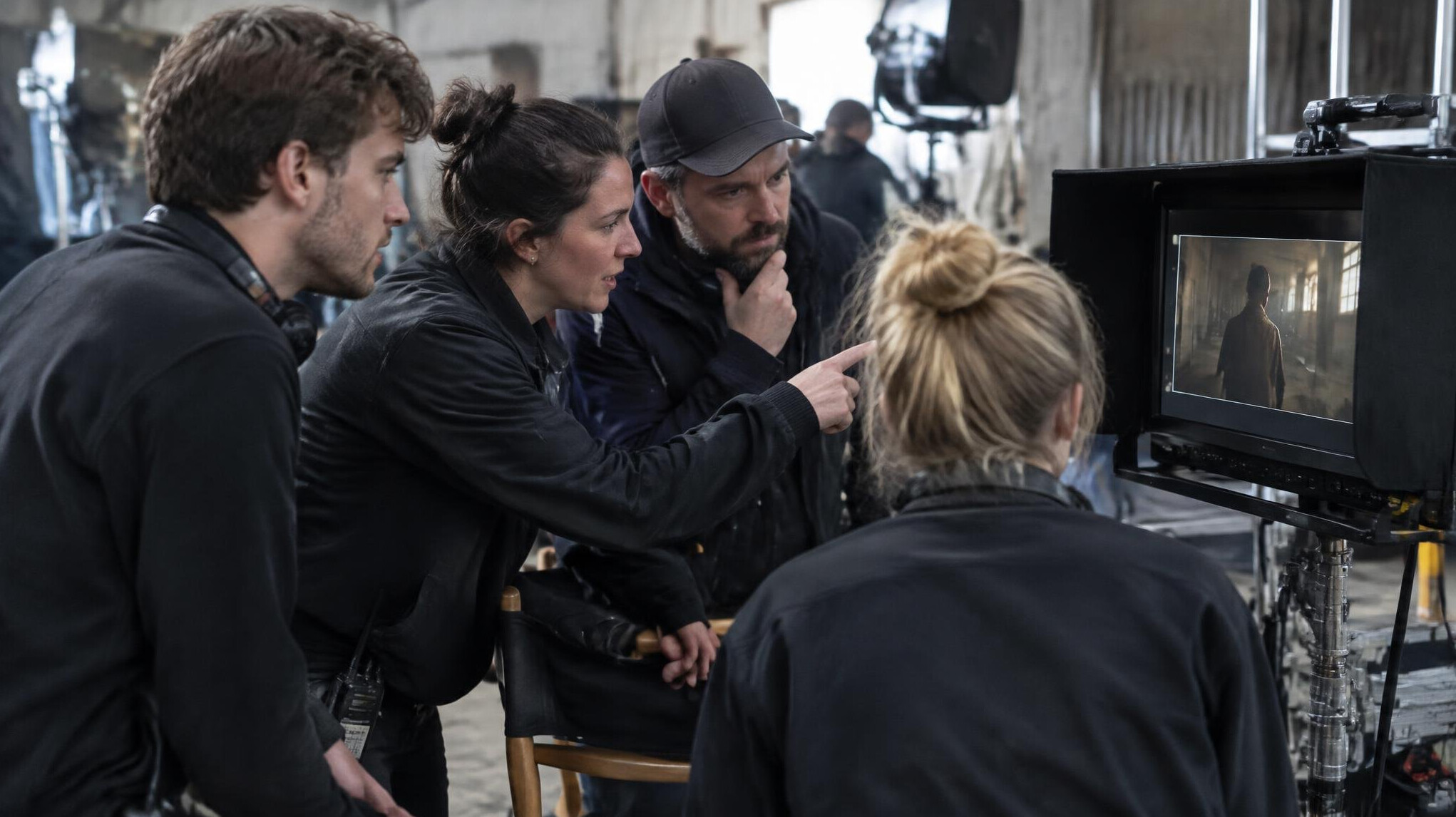 Small British production crew reviewing a monitor together on set